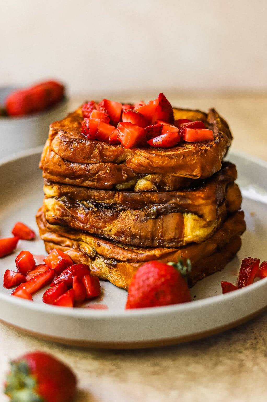A stack of Nutella stuffed french toast topped with macerated strawberries and whipped cream