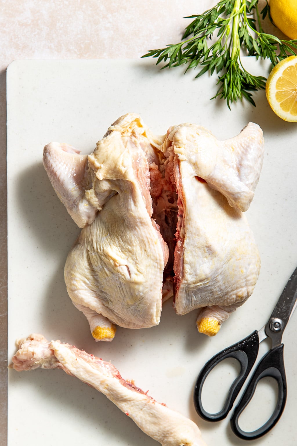 Whole chicken on a cutting board with spine removed