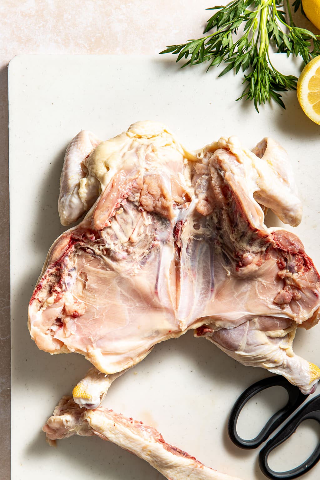 chicken laid out flat after spatchcocking on a cutting board