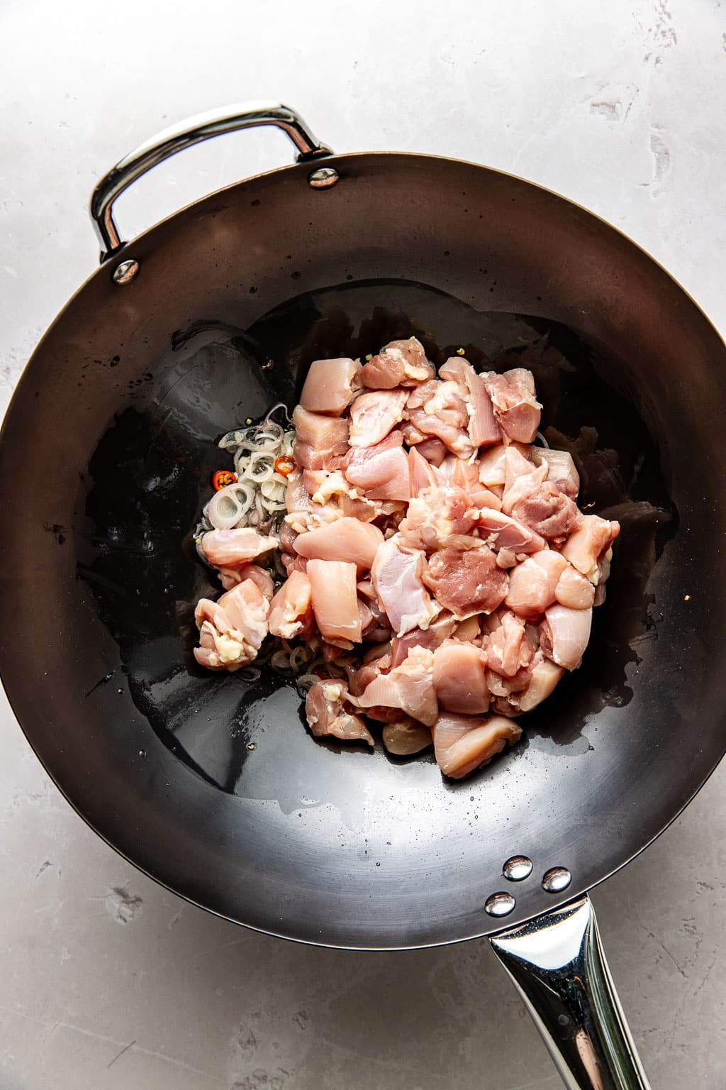 raw chicken added to a wok 