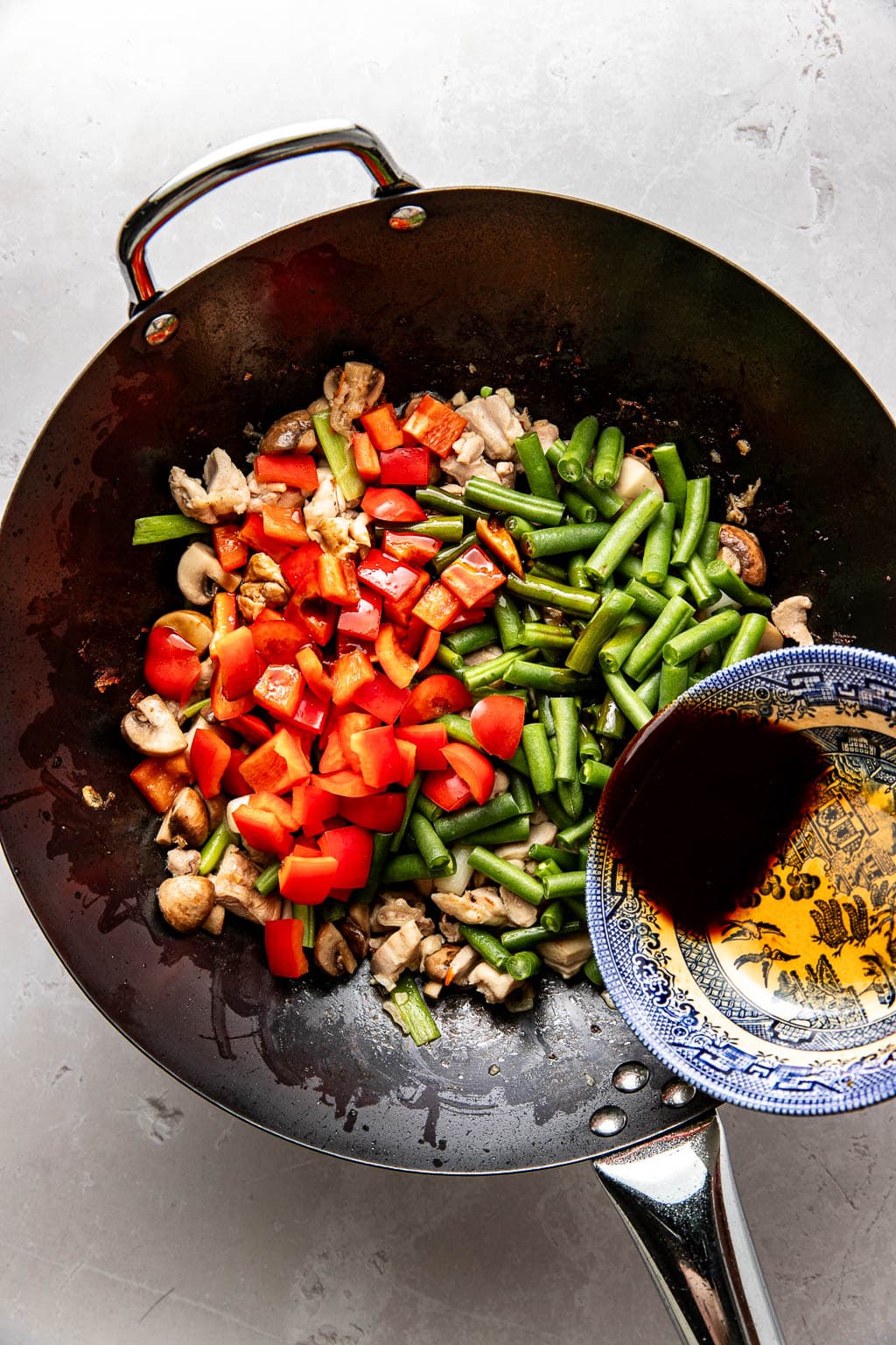 stir fry sauce being poured into a wok