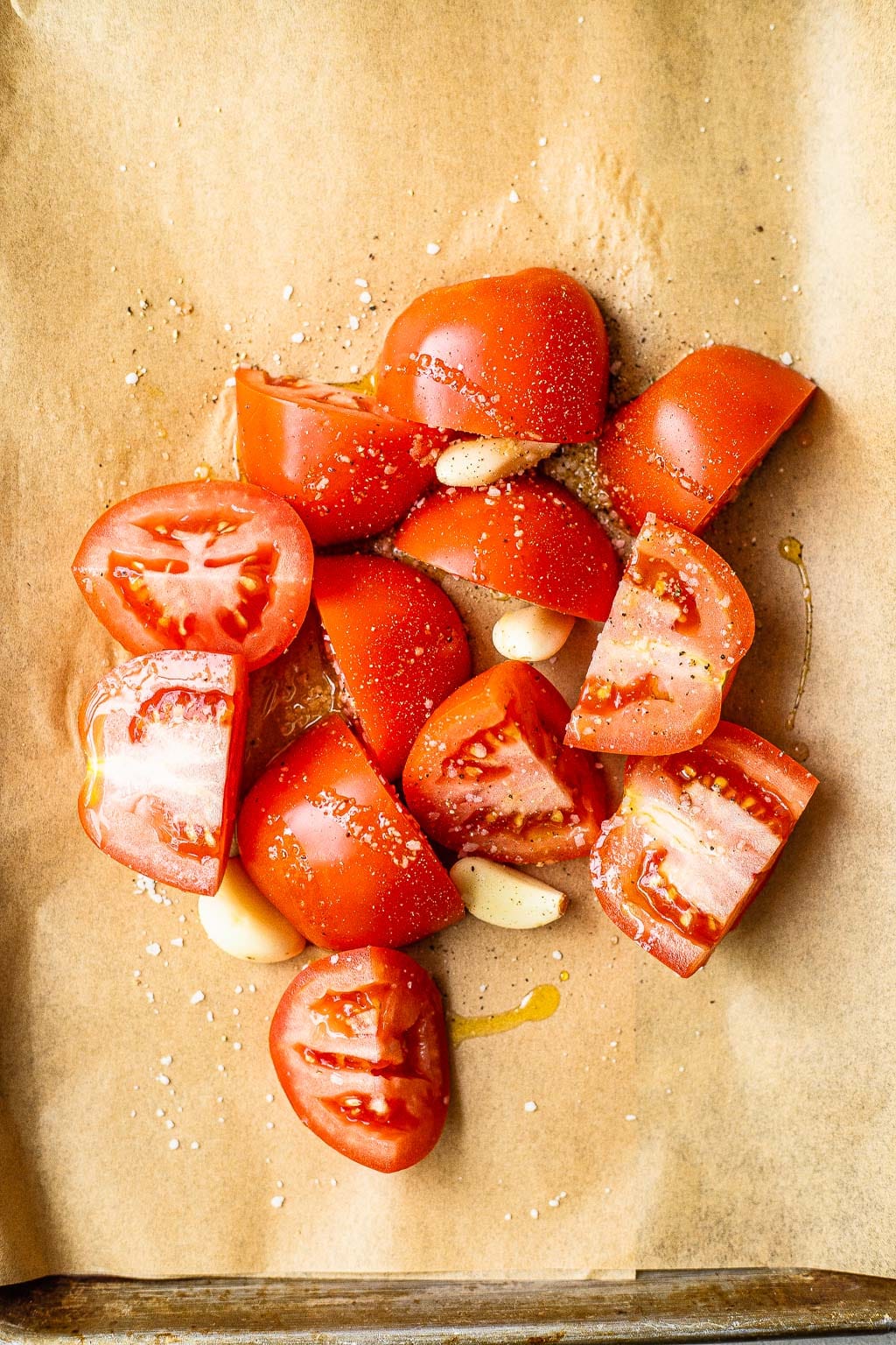 quartered tomatoes and garlic on a baking sheet 