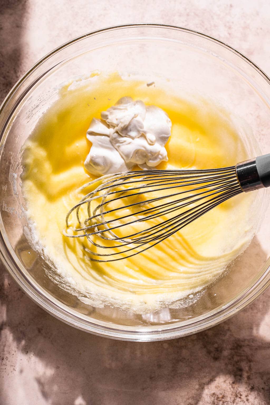 Sour cream being whisked into a butter and sugar mixture