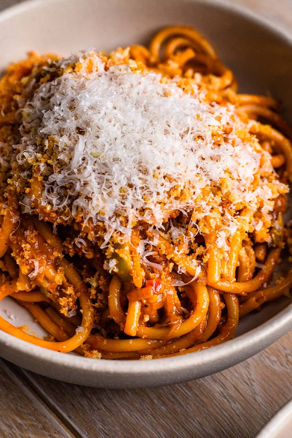 A bowl of caramelized shallot pasta topped with a heap of Parmesan. 