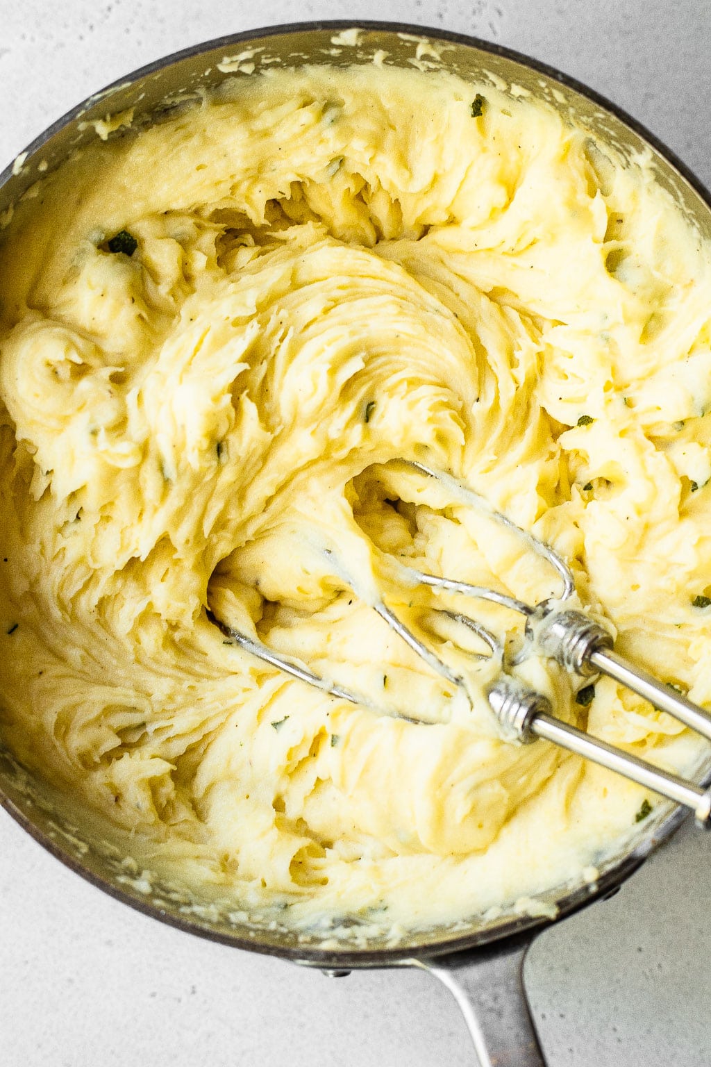 Mashed potatoes being whipped with a hand mixer 