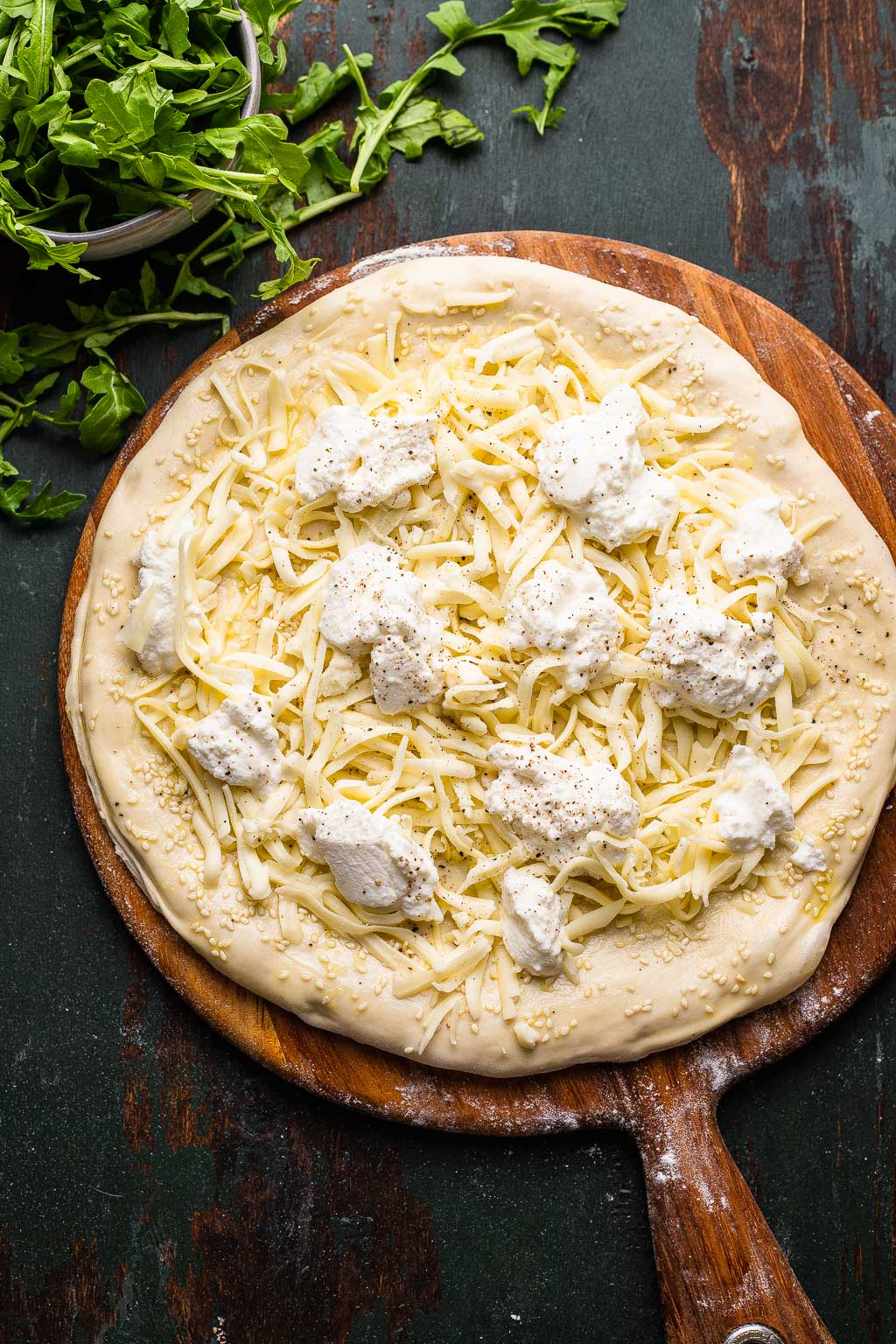A white pizza topped with cheese, ready to be baked. 