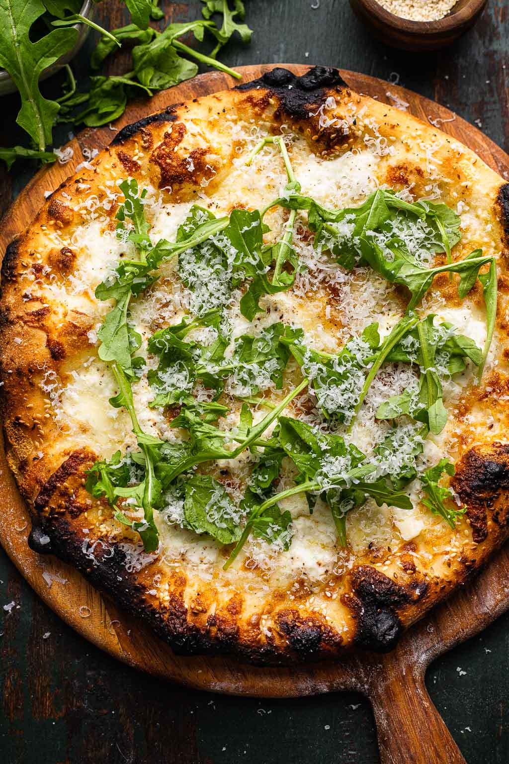 Overhead view of a pizza bianca topped with Parmesan and arugula. 