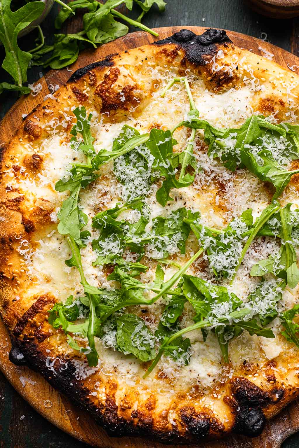 Overhead view of a pizza bianca topped with Parmesan and arugula. 
