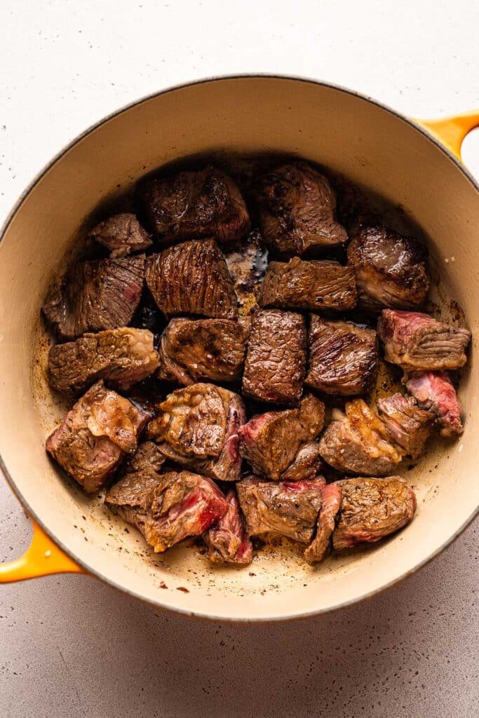 A process shot showing beef chuck browning in a dutch oven. 