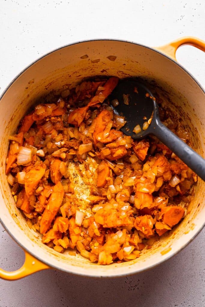 A process shot showing vegetables for beef burgundy in a dutch oven. 