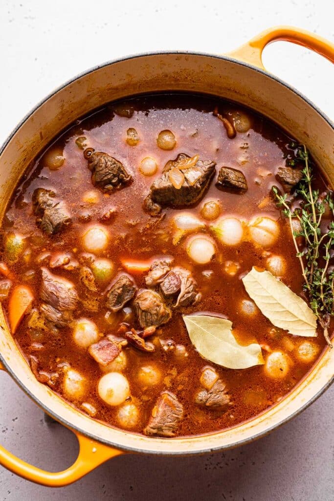 A process shot showing beef burgundy stew braising in a dutch oven. 