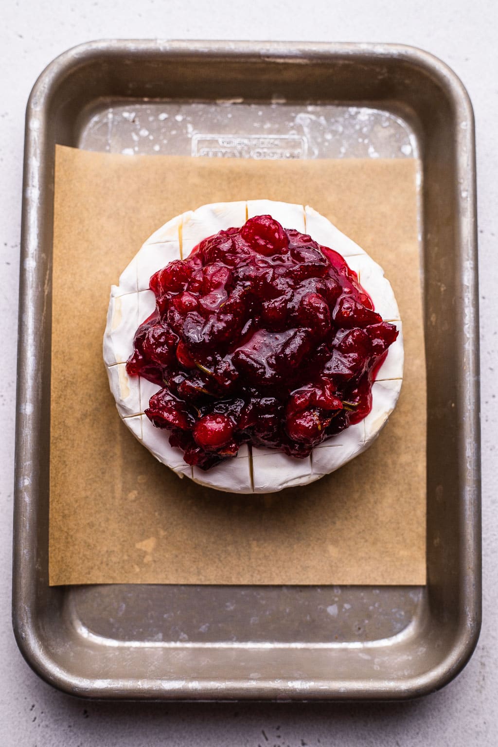 Brie cheese scored and topped with cranberry sauce