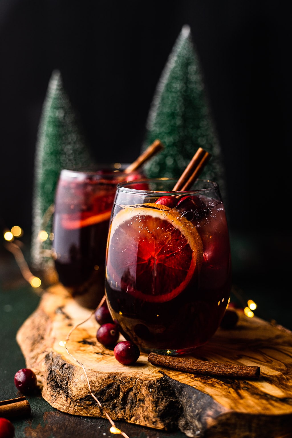 Two glasses of holiday sangria garnished with a cinnamon stick. 