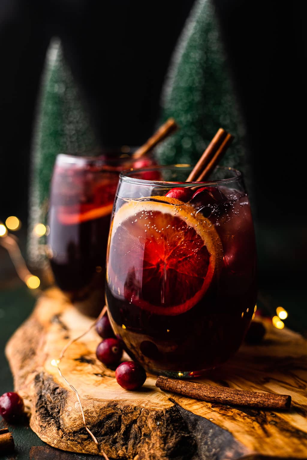 Two glasses of holiday sangria garnished with a cinnamon stick. 