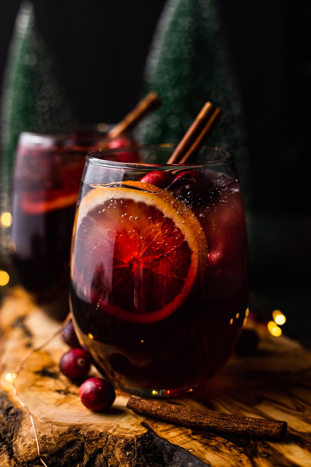 Two glasses of holiday sangria garnished with a cinnamon stick. 