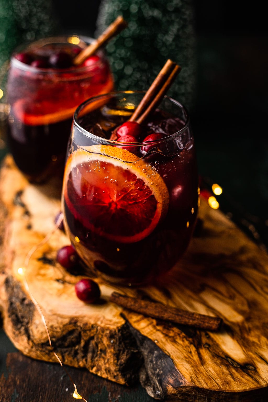 Two glasses of holiday sangria garnished with a cinnamon stick. 