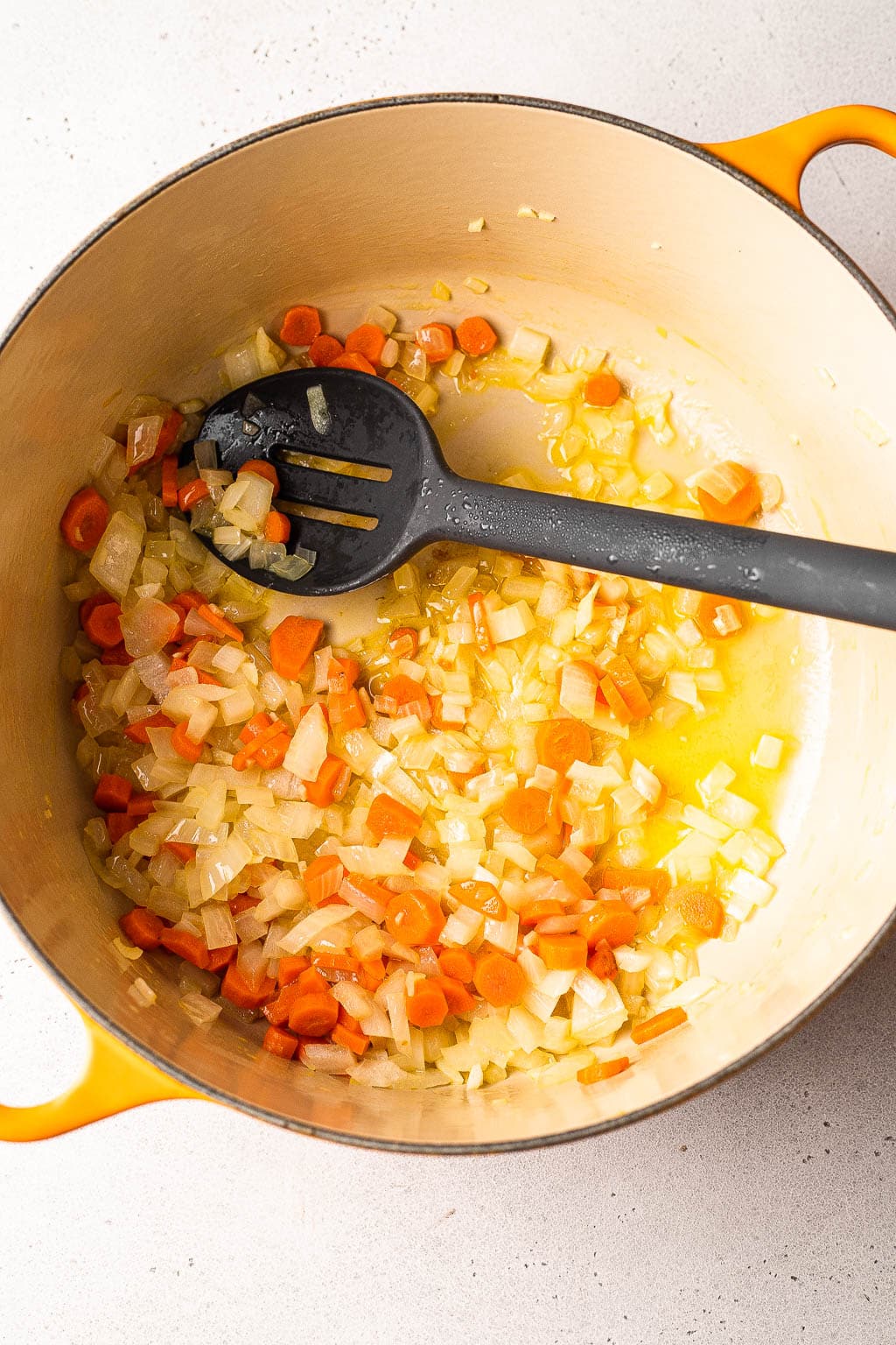 Veggies added to a dutch oven with melted butter 