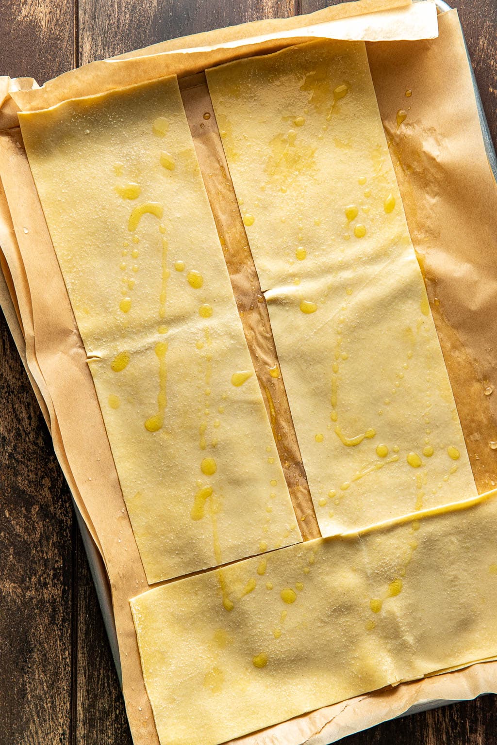 Lasagna noodles cooling between sheets of parchment paper. 