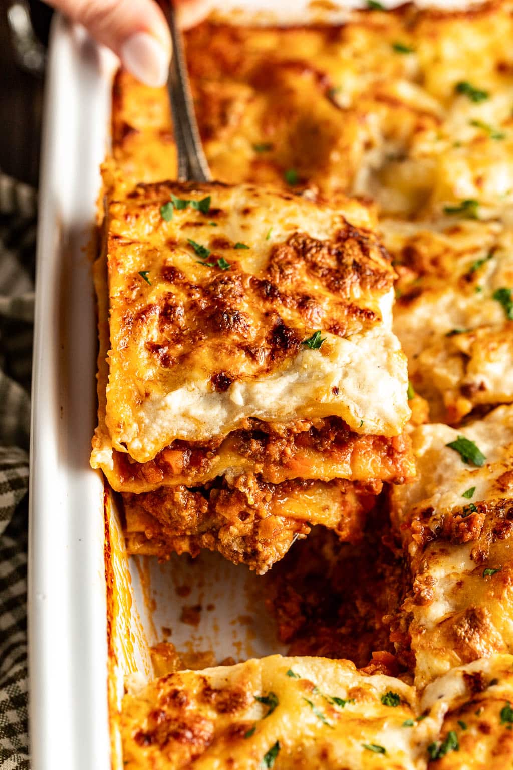 Removing a slice of lasagna bolognese from a pan. 
