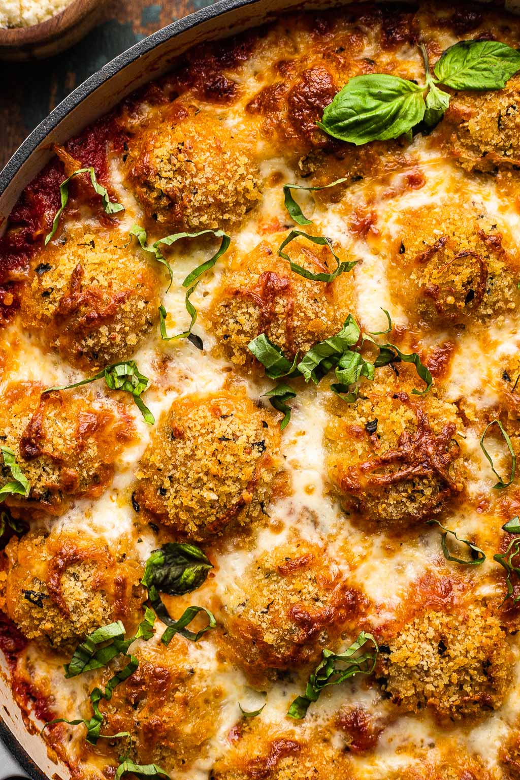 Baked chicken parm meatballs in a skillet. 