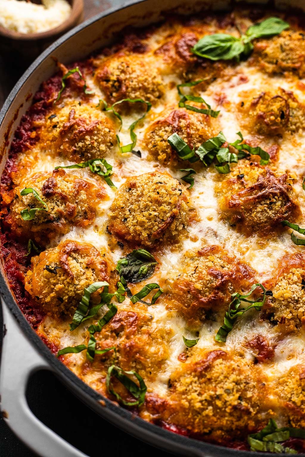Baked chicken parm meatballs in a skillet. 