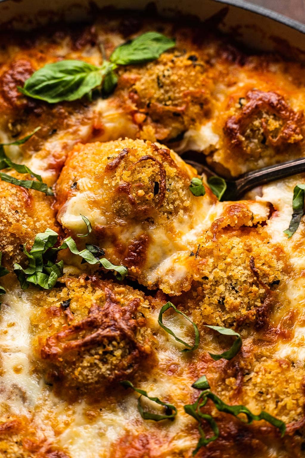 Baked chicken parm meatballs in a skillet. 