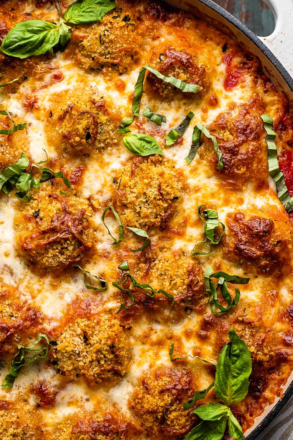 Baked chicken parmesan meatballs in a skillet. 