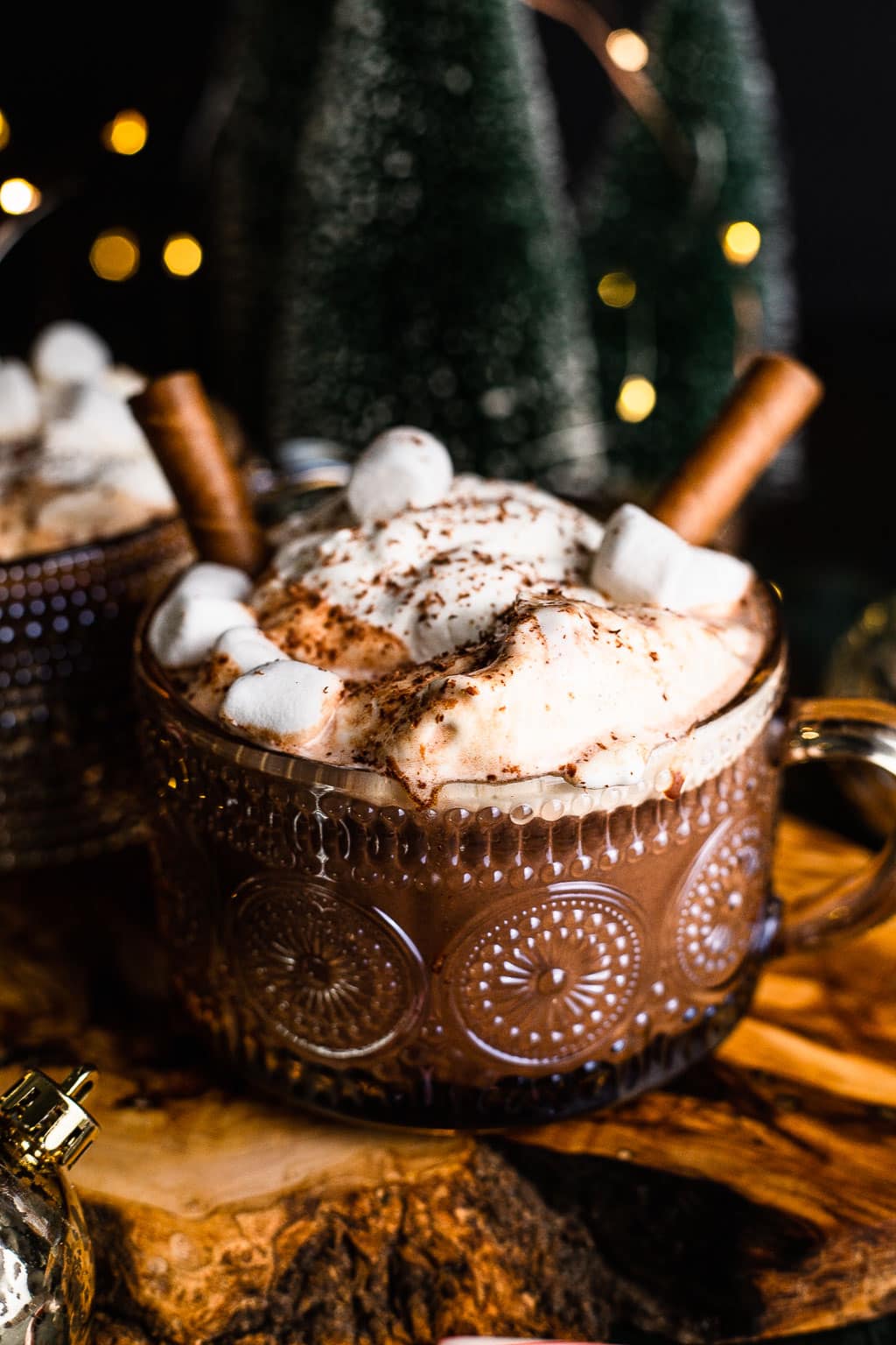 A mug of chocolate topped with whipped cream, marshmallows, and cookie straws. 