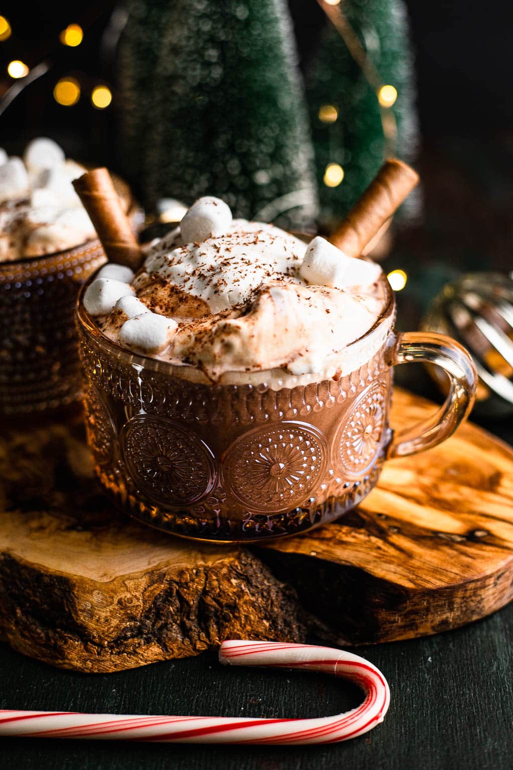 A mug of chocolate topped with whipped cream, marshmallows, and cookie straws. 