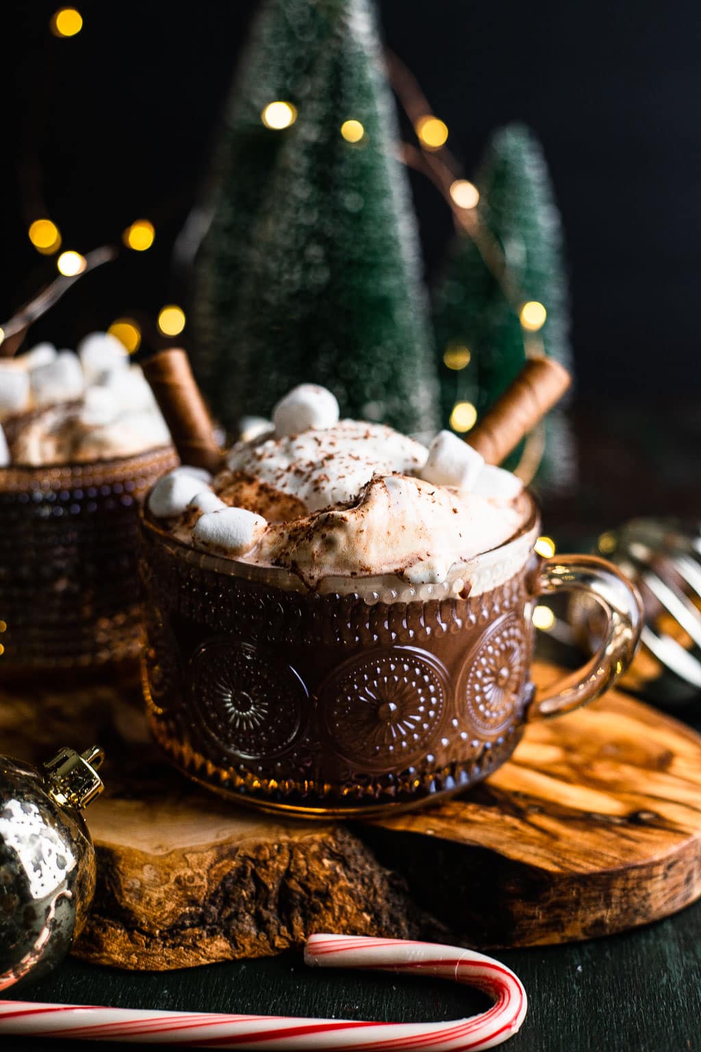 A mug of chocolate topped with whipped cream, marshmallows, and cookie straws. 