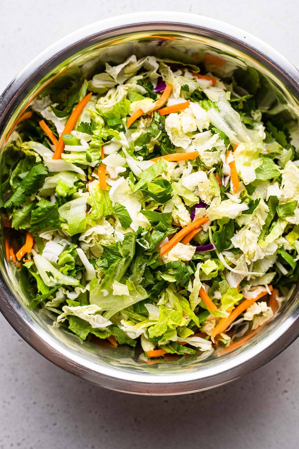 Shredded cabbage, lettuce, and carrots in mixing bowl 