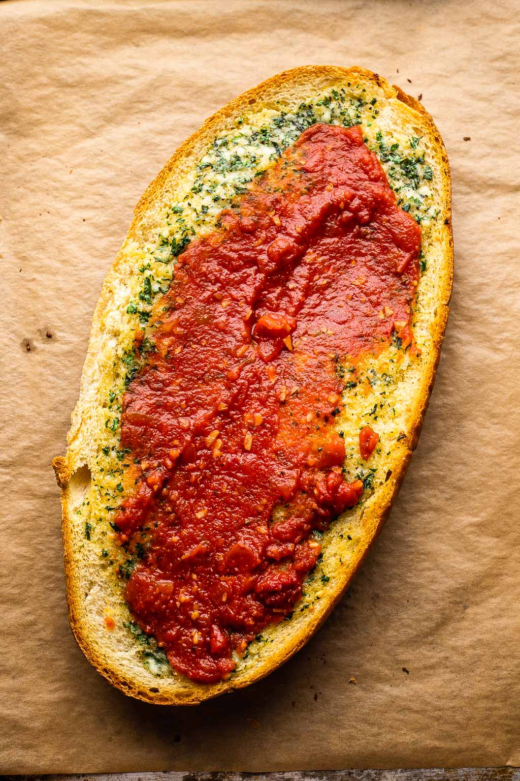 a loaf of french bread spread with garlic butter and pizza sauce