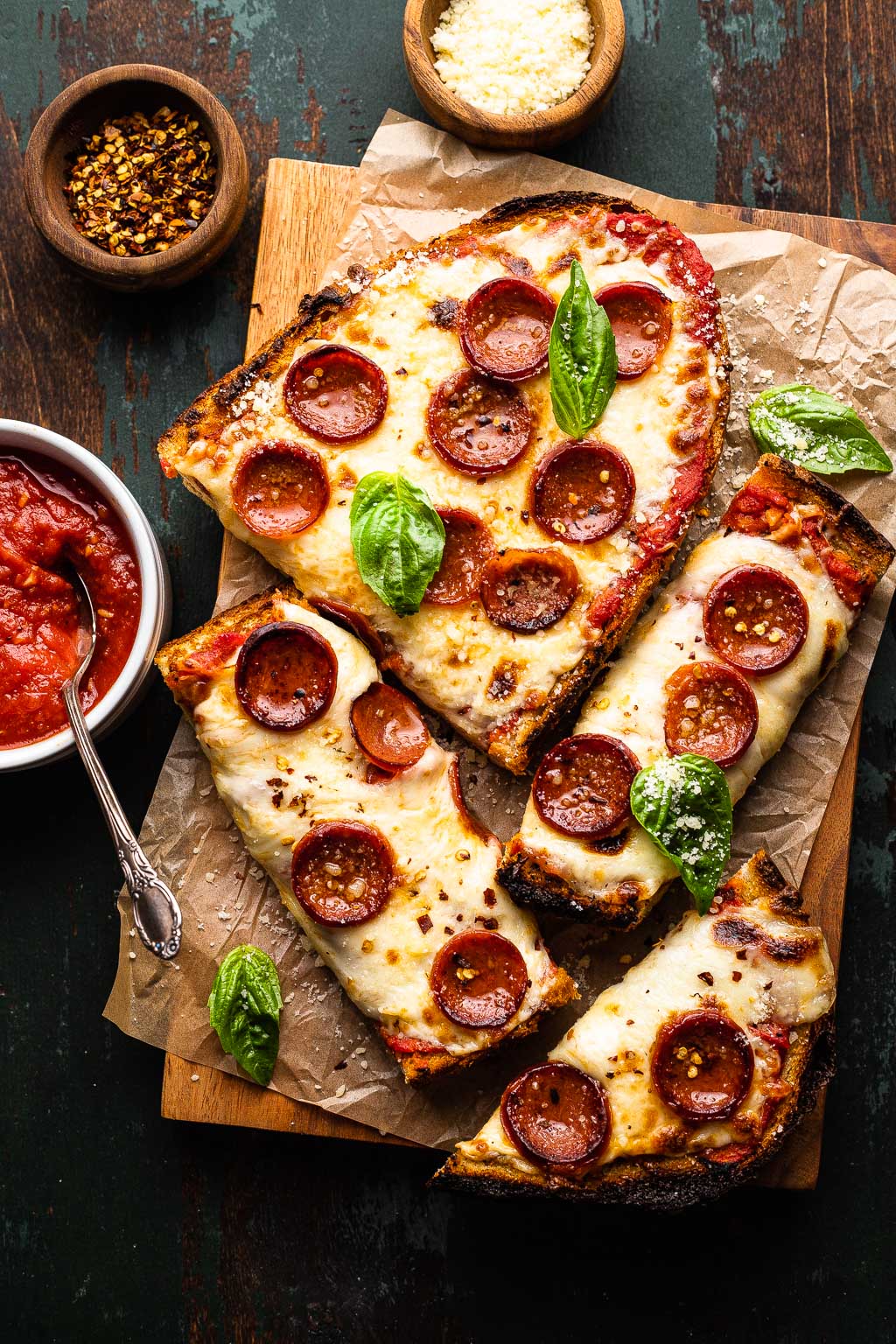 pepperoni french bread pizza, partially sliced and topped with basil