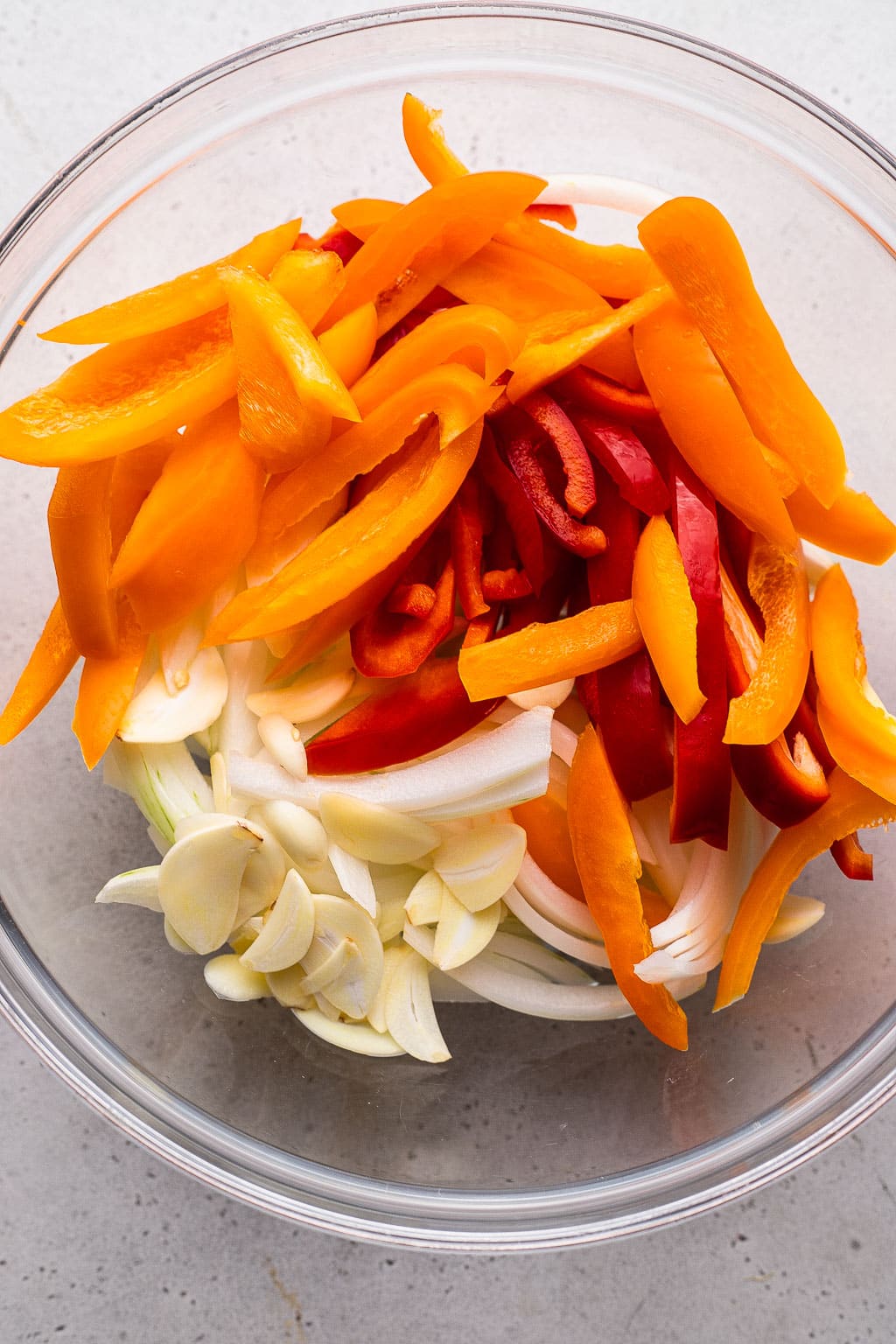Raw peppers and onions in a mixing bowl 