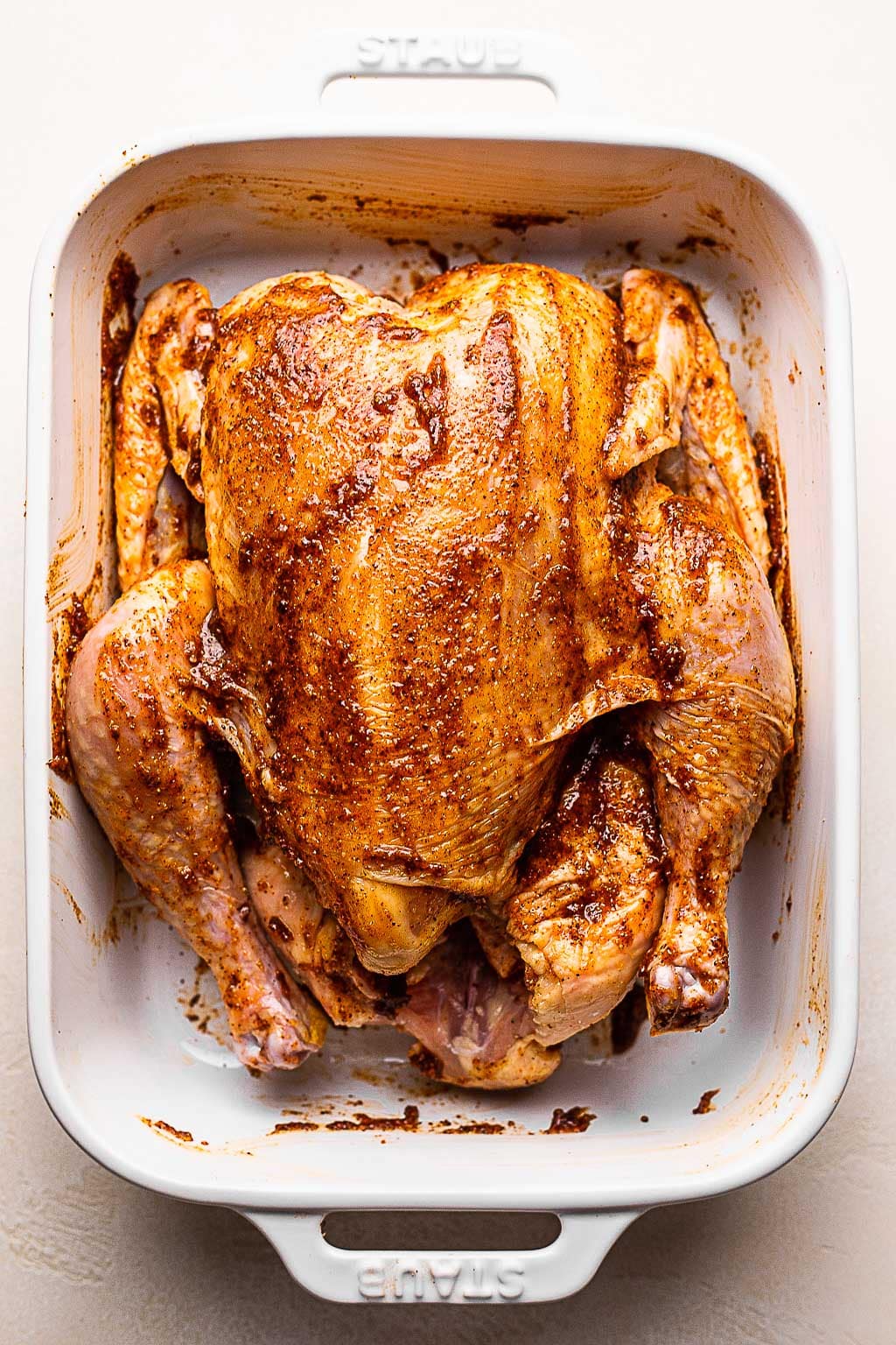 A whole chicken slathered with a spice rub 