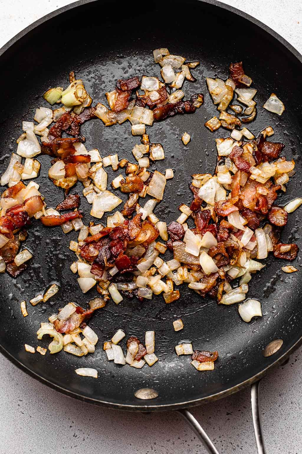 Cooked bacon and onions in a skillet 
