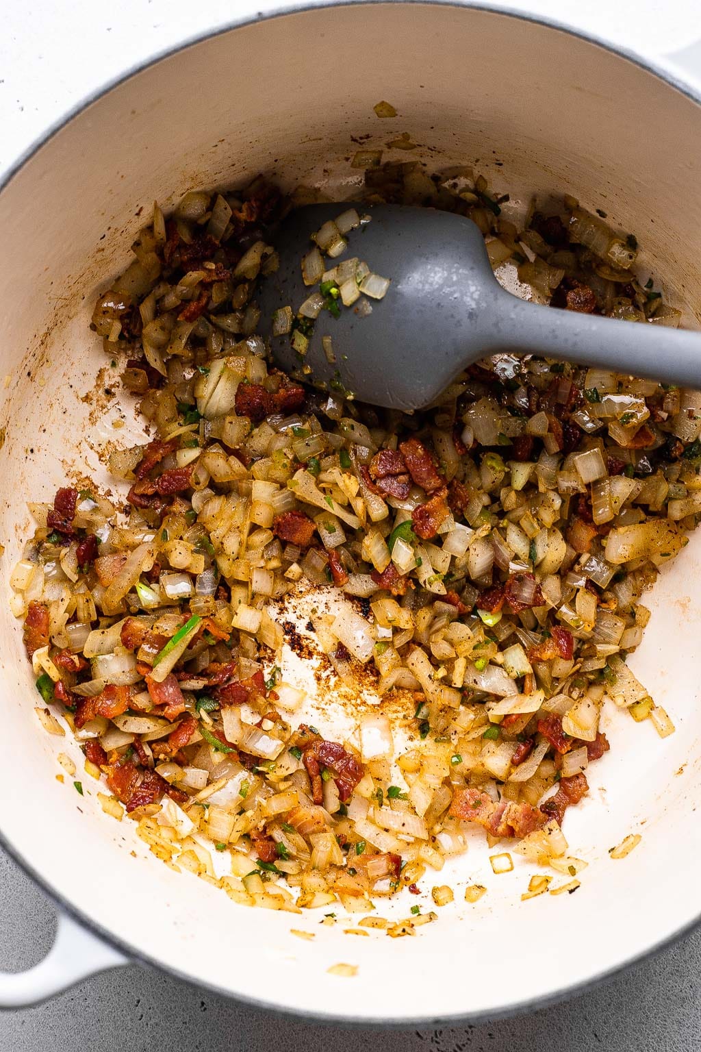process shot showing cooked bacon, onion, and jalapeño in a pot 