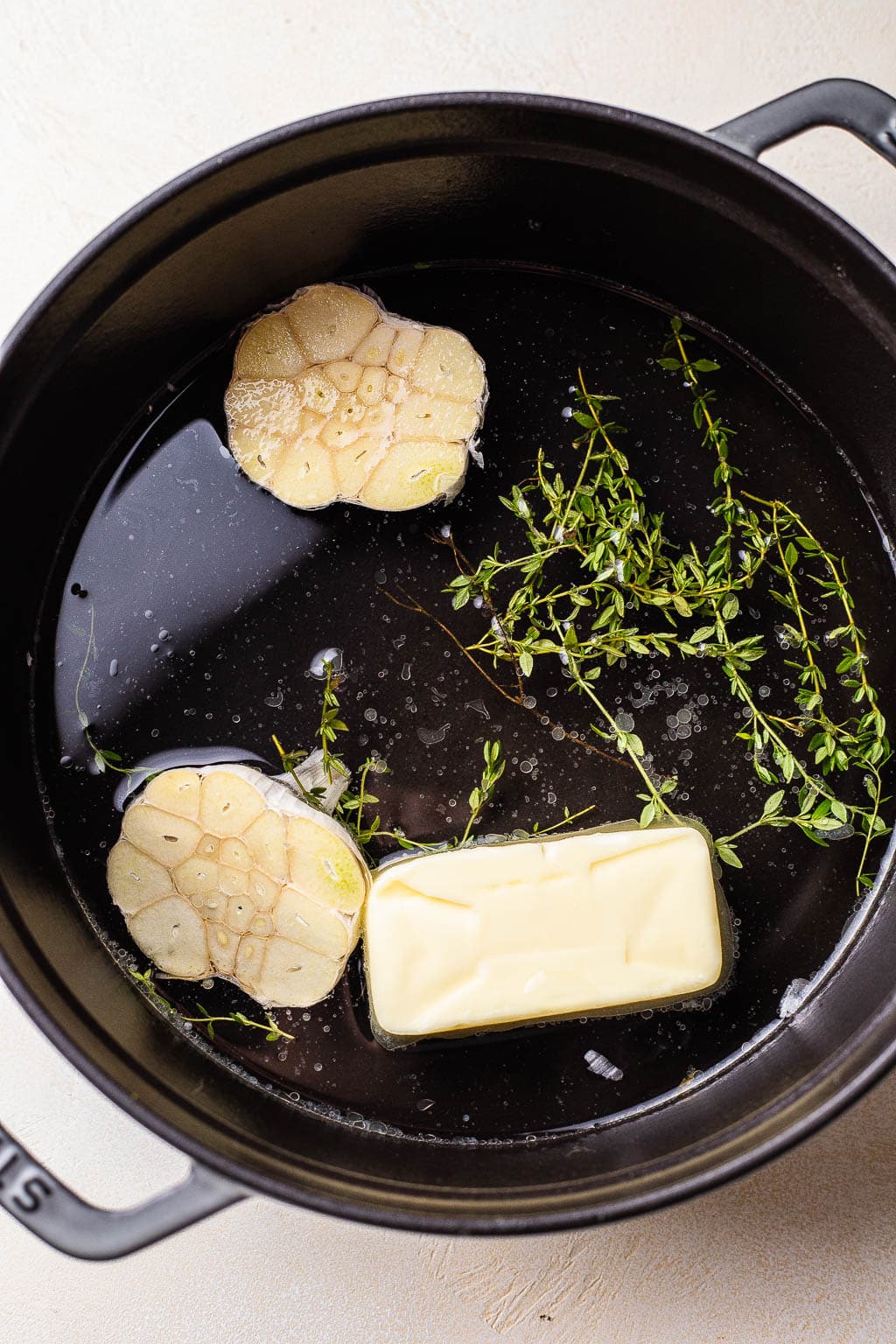Garlic, herbs, and butter in a Dutch oven 