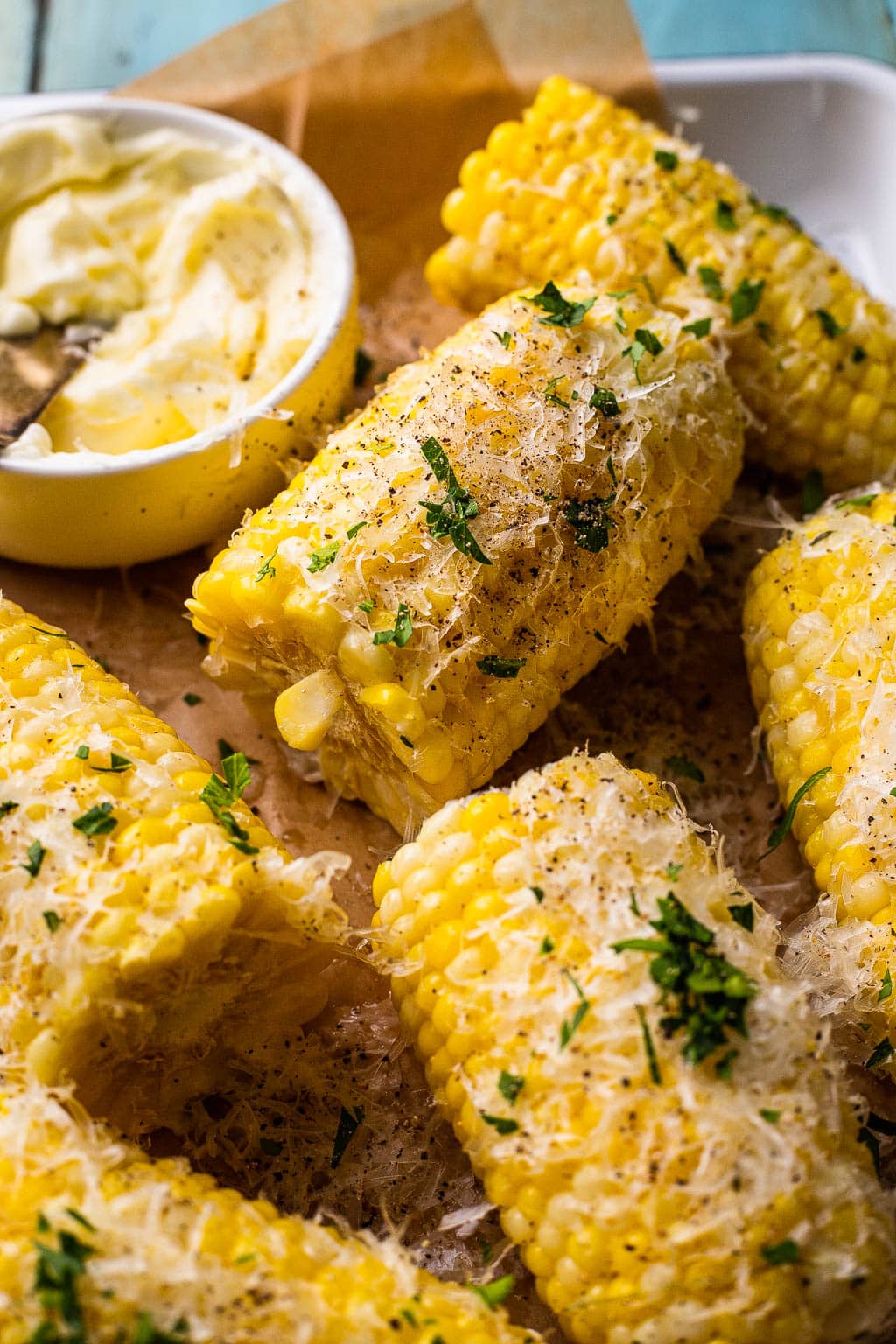 Boiled corn cobs cut in half and seasoned with parmesan and herbs 