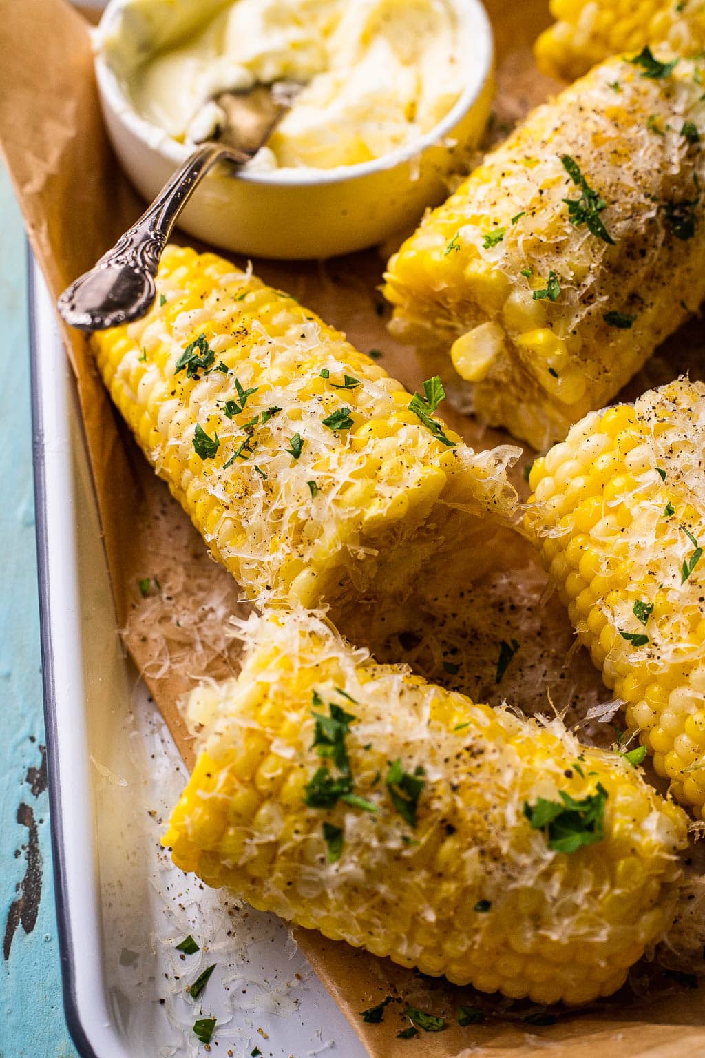 Boiled corn cobs cut in half and seasoned with parmesan and herbs 