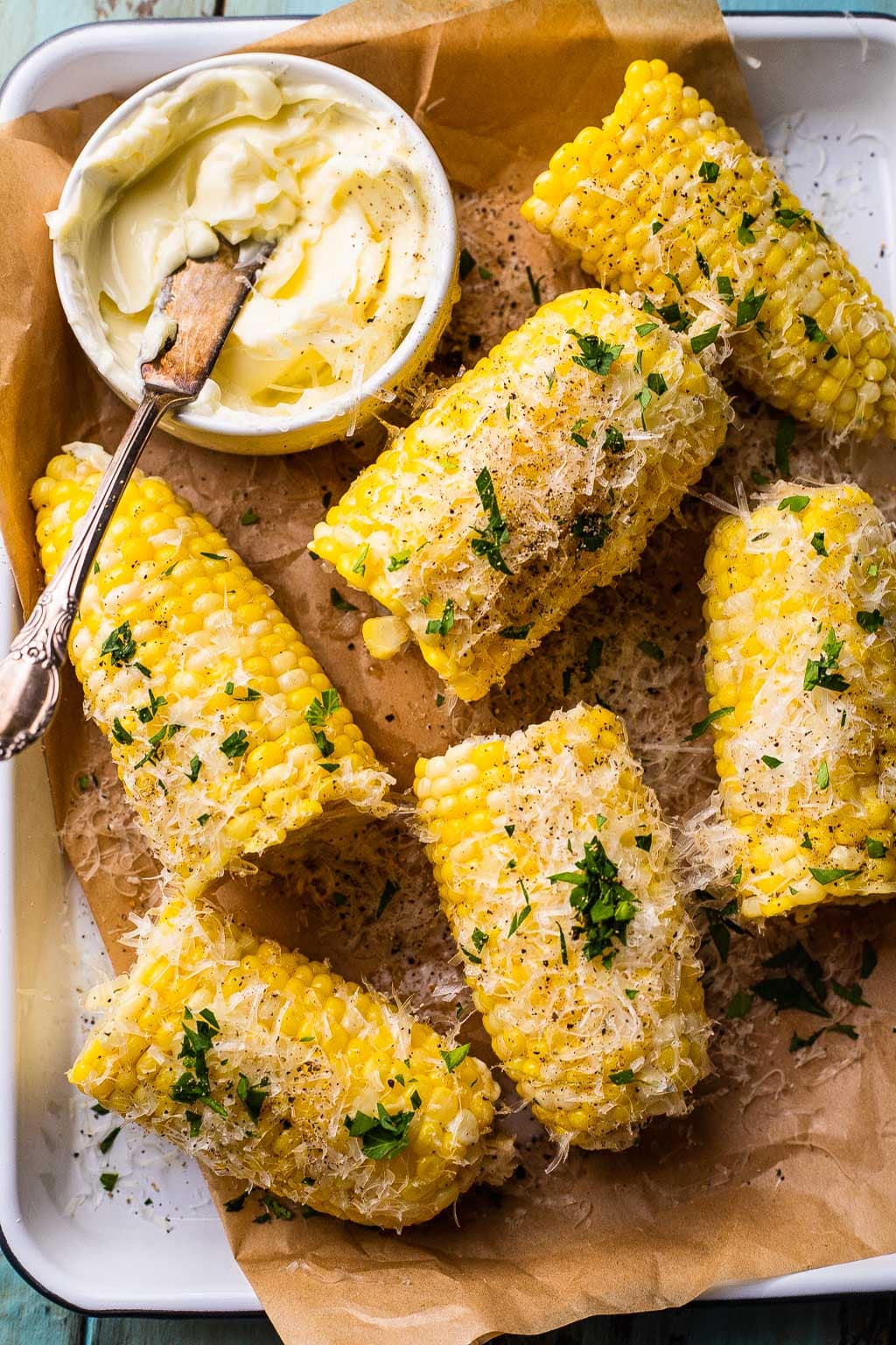 Boiled corn cobs cut in half and seasoned with parmesan and herbs 