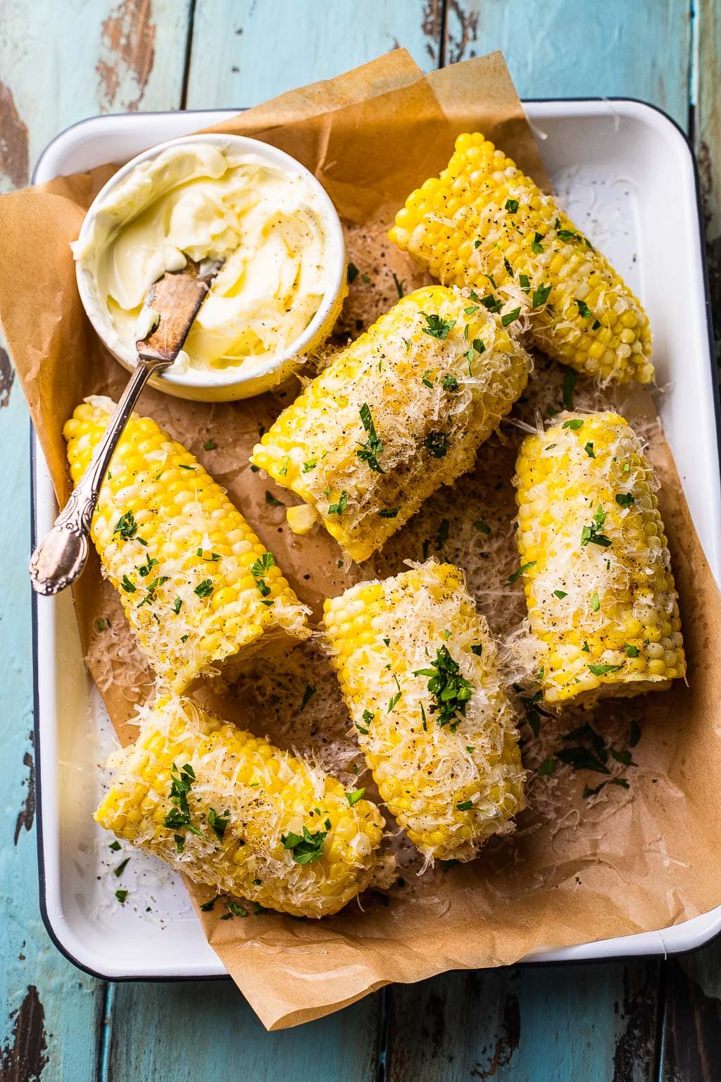 Boiled corn cobs cut in half and seasoned with parmesan and herbs 