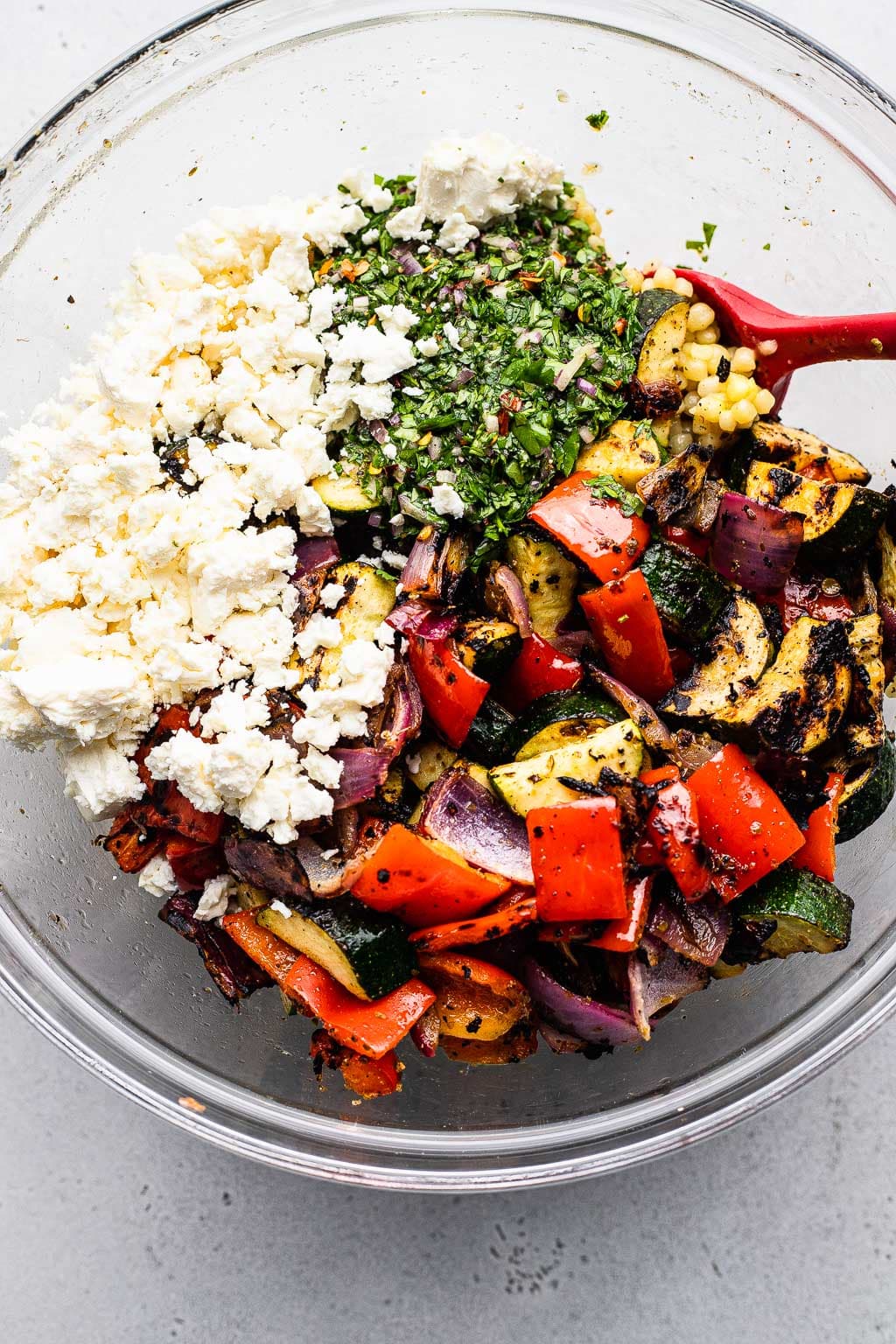Grilled vegetables, couscous, chimichurri, and feta in a bowl 