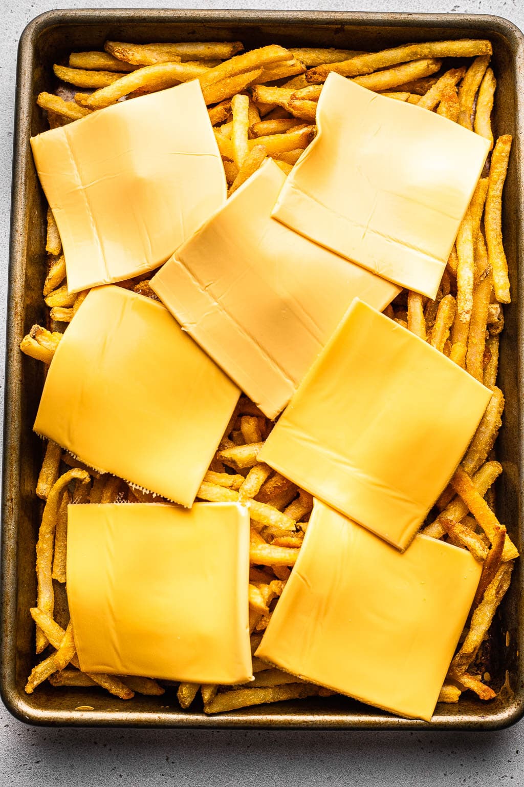 Cheese-topped fries on a sheet pan. 
