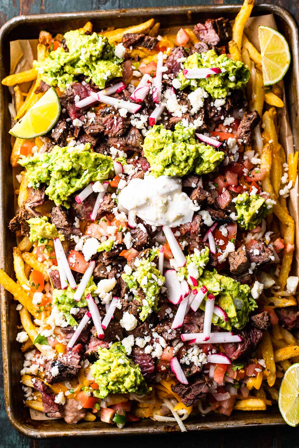 Loaded California-style carne asada fries on a sheet pan 