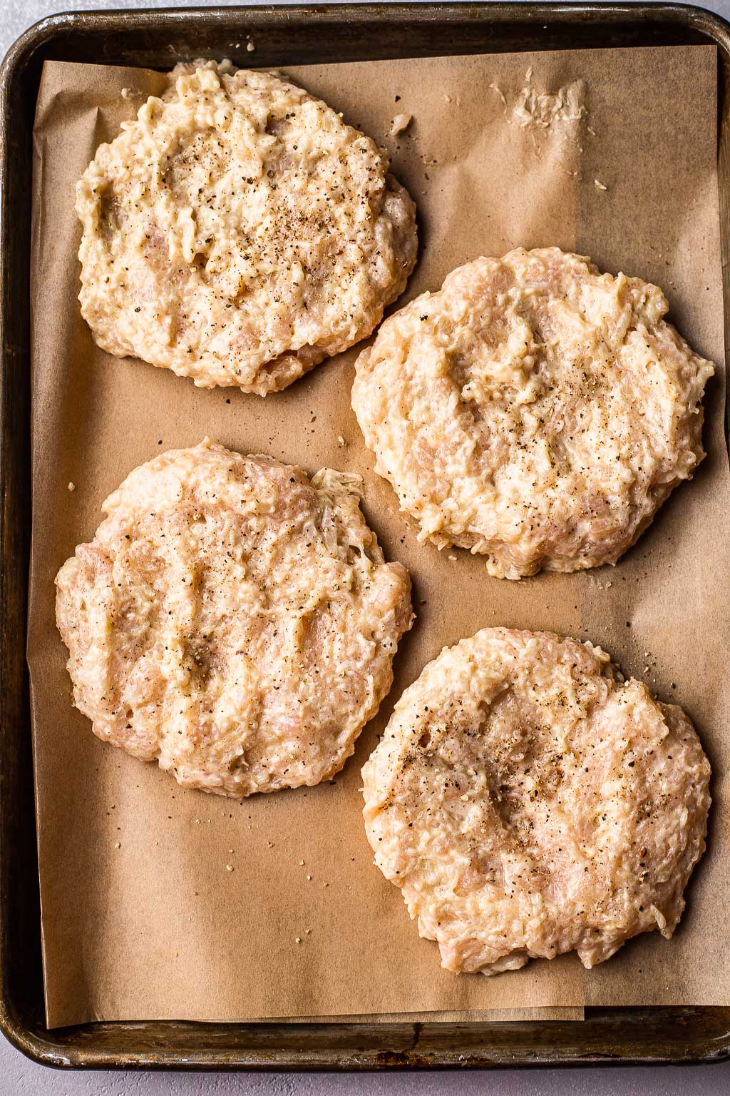 Raw chicken patties on a baking sheet 