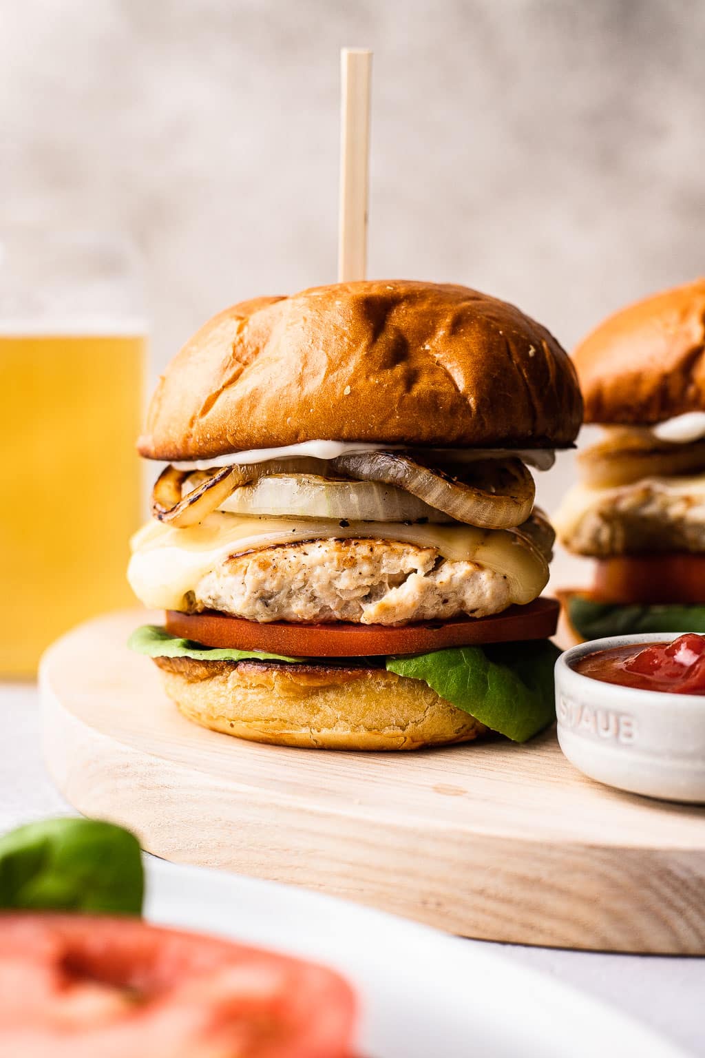 A chicken burger on a wooden serving board. 