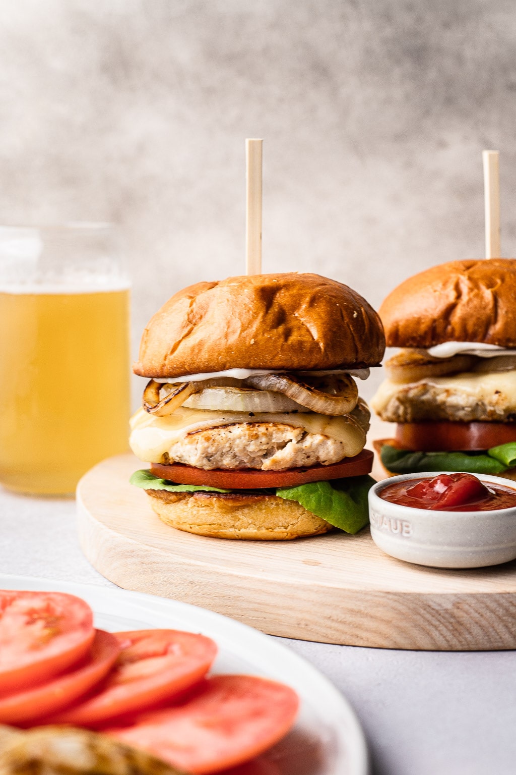 A chicken burger on a wooden serving board. 