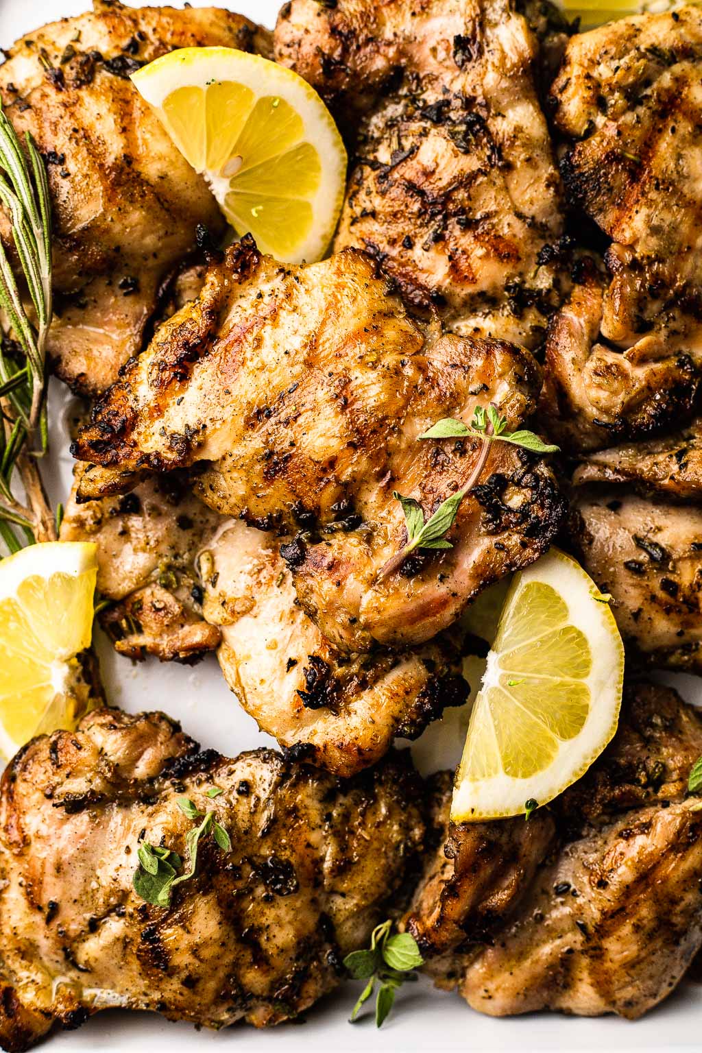 An overhead view of grilled lemon herb chicken on a baking tray. 