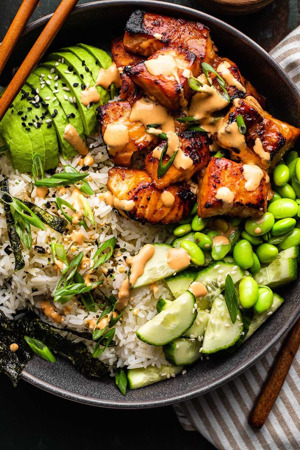 A salmon bowl with sauce drizzled over top 